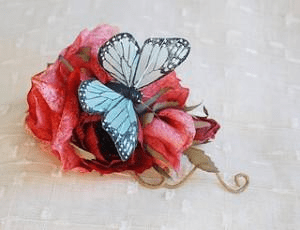 A light blue butterfly resting on a red flower